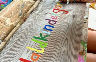 Kind mit Pinsel bemalt Holzschild für Waldkindergarten