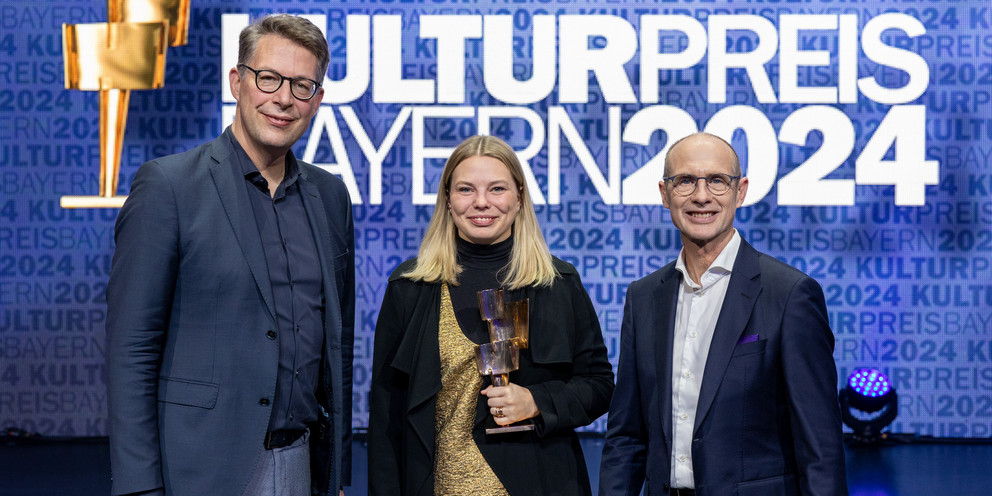 Preisträgerin Dr. Johanna Zimmermann steht neben Minister Markus Blume (l.) und Bayernwerk-Chef Dr. Egon Leo Westphal (r.).