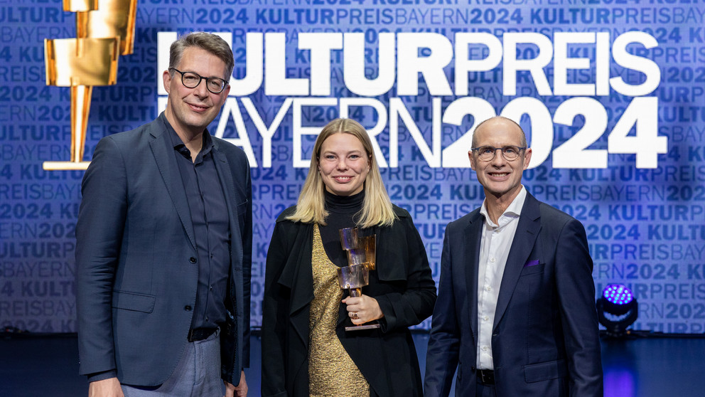 Preisträgerin Dr. Johanna Zimmermann steht neben Minister Markus Blume (l.) und Bayernwerk-Chef Dr. Egon Leo Westphal (r.).