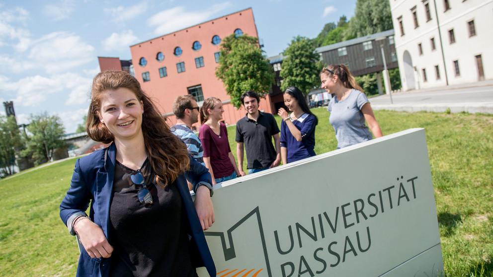 Gruppe Studierender am Universitätsschild auf der Innwiese