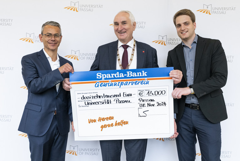 Michael Gruber, Vorstandsvorsitzender der Sparda-Bank Ostbayern eG (li), übergab gemeinsam mit Stephan Brandler, Leiter der Sparda-Bank-Filiale Passau (re) den Spendenscheck an Universitätspräsident Prof. Dr. Ulrich Bartosch (Mitte); Foto: Universität Passau