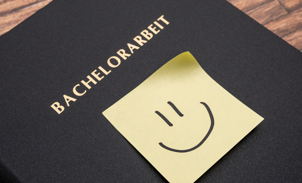 Ansicht einer fertigen Bachelorarbeit, schwarze Hardcoverbindung mit Smiley als Post-it auf der Vorderseite